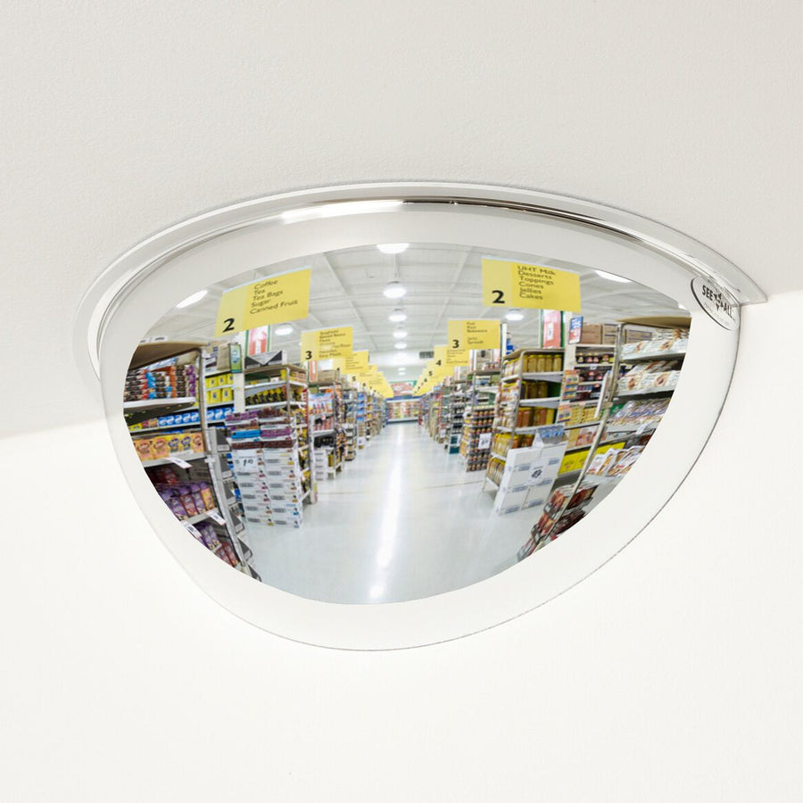 Half convex mirror in a store reflecting an aisle with shelves and signs.