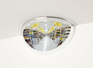 Half convex mirror in a store reflecting an aisle with shelves and signs.